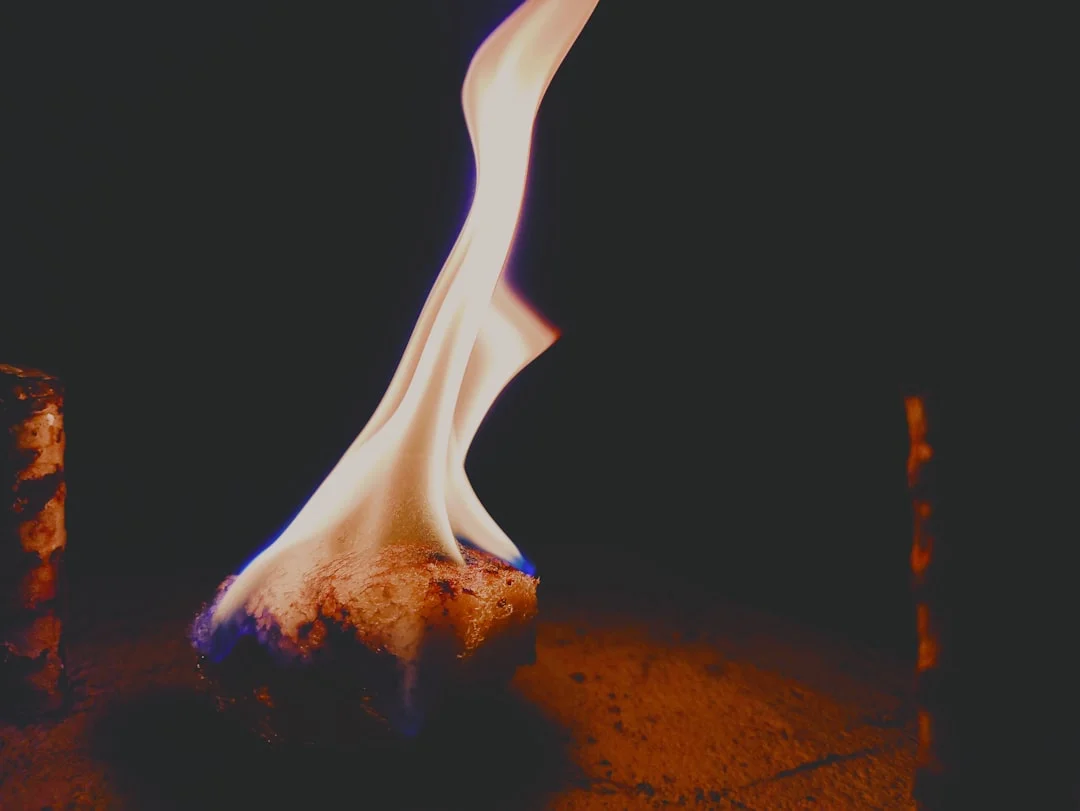 A close-up of a gas fireplace burner pan showing the wrong type of sand, highlighting the potential dangers of using play sand in a gas fireplace.