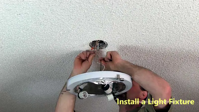 A person is installing a light fixture