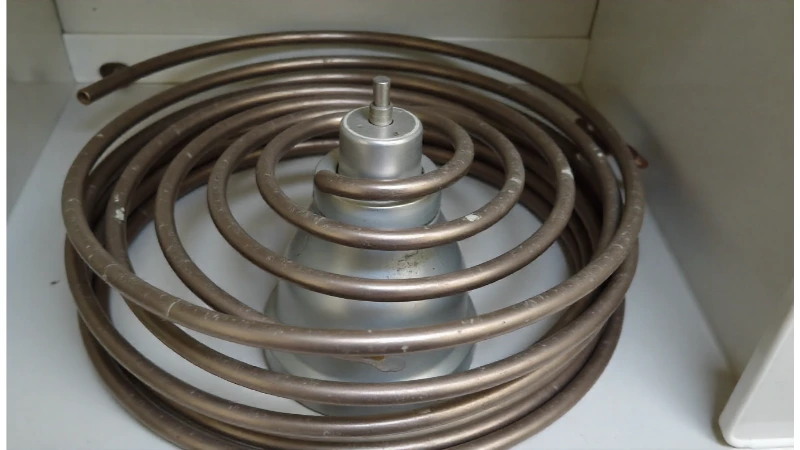 A close-up view of a brand new, metallic dryer heating element coil before installation.