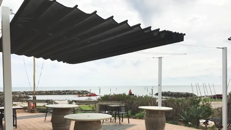 black shaderunner retractable sail providing shade for a seaside venue