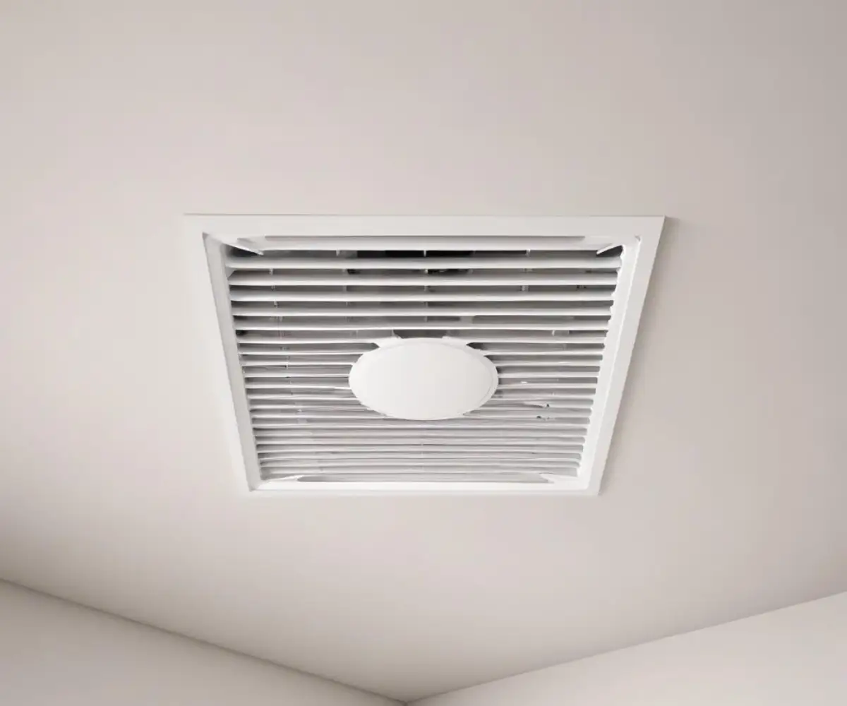 A white, square ventilation fan grille installed flush with a plain white ceiling.
