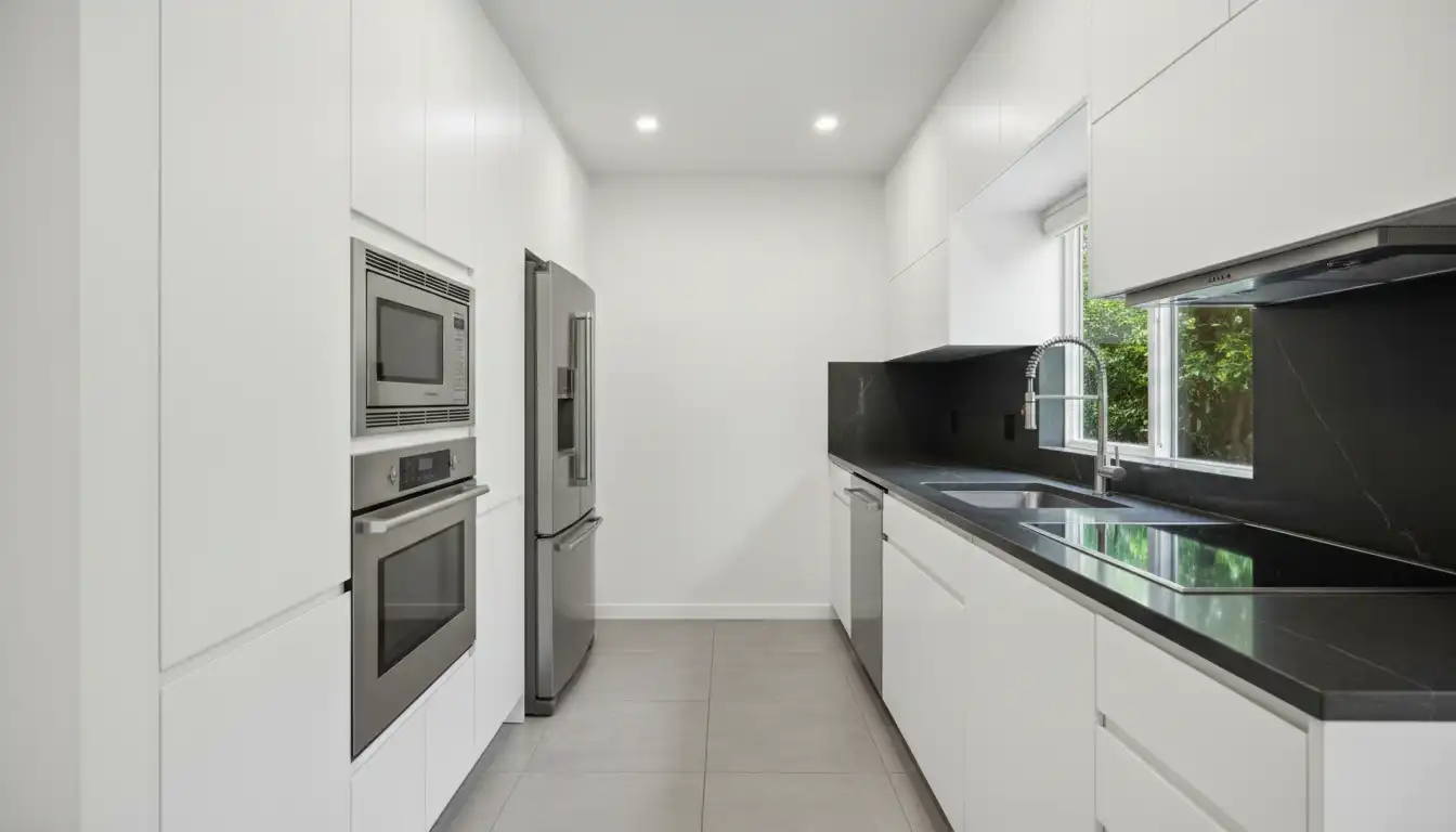A compact 8x8 galley kitchen layout with parallel white cabinets, dark countertops, and stainless steel appliances.