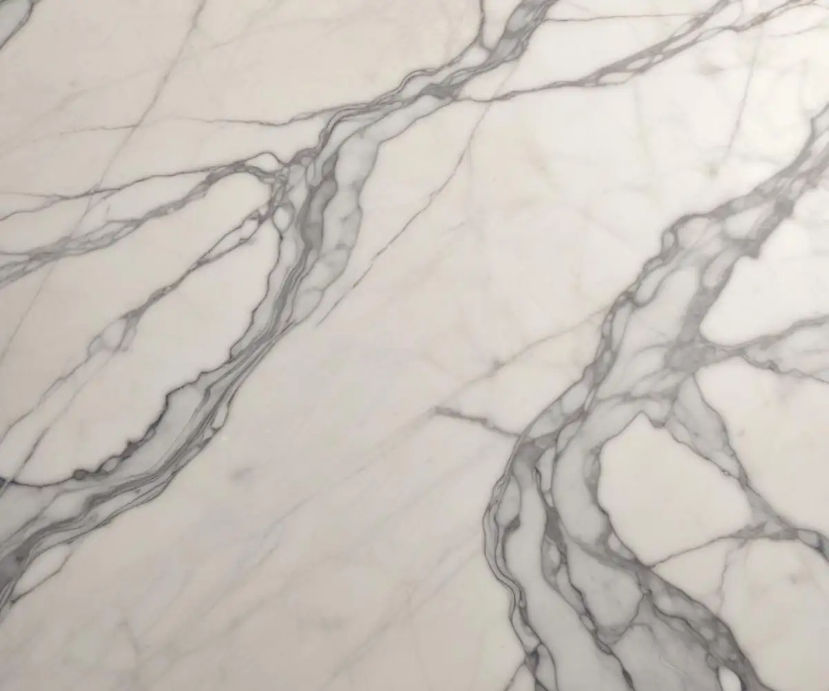 A close-up of an aged marble countertop with soft, grey veining and a smooth, matte finish.