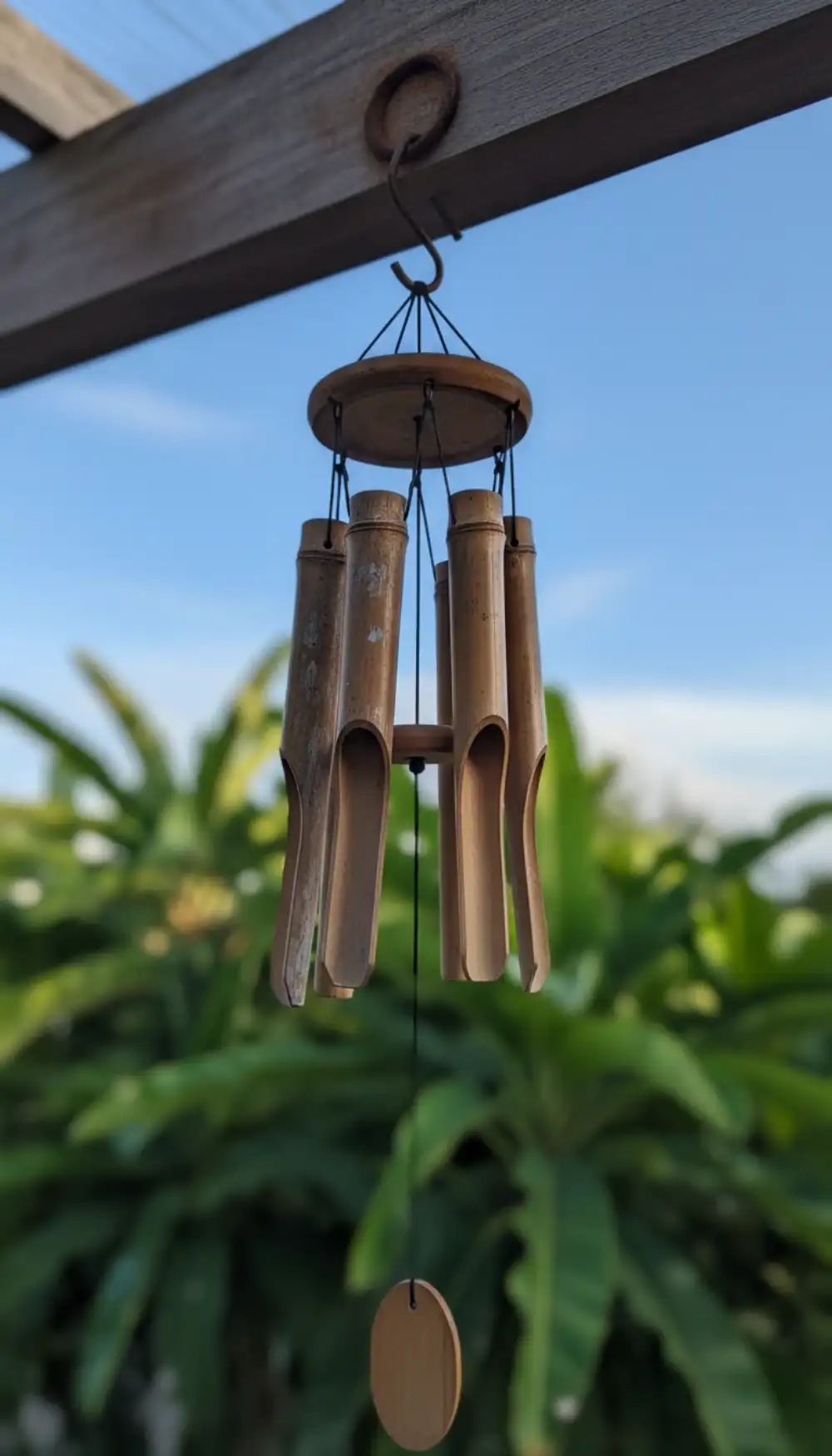 Bamboo wind chimes hanging near a balcony window