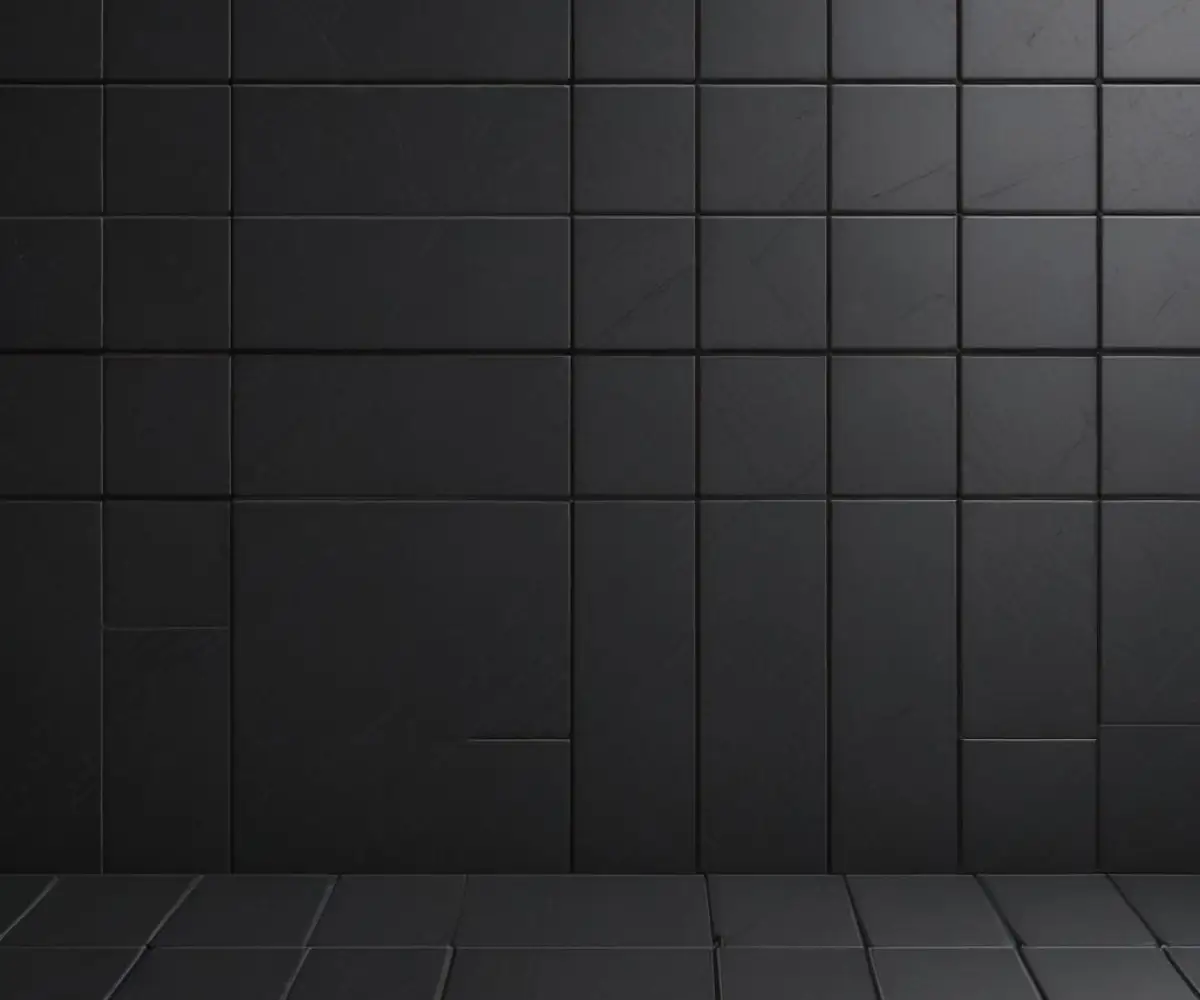 A seamless surface of matte black square tiles with matching black grout, creating a modern and textured background.