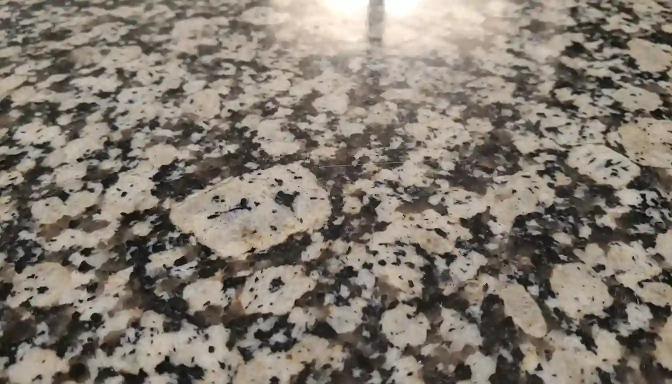 A close-up view of a polished, speckled used granite countertop slab showcasing its natural stone pattern and texture.