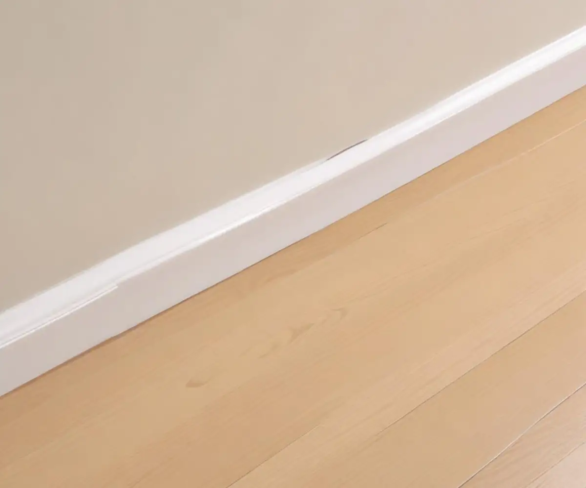 White PVC quarter round moulding installed neatly between a light-colored floor and a white baseboard.