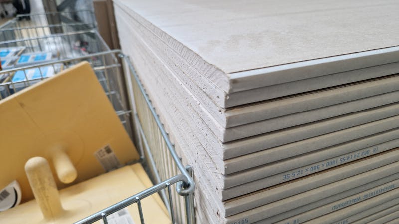 A neat stack of standard gypsum drywall panels at a home improvement store.