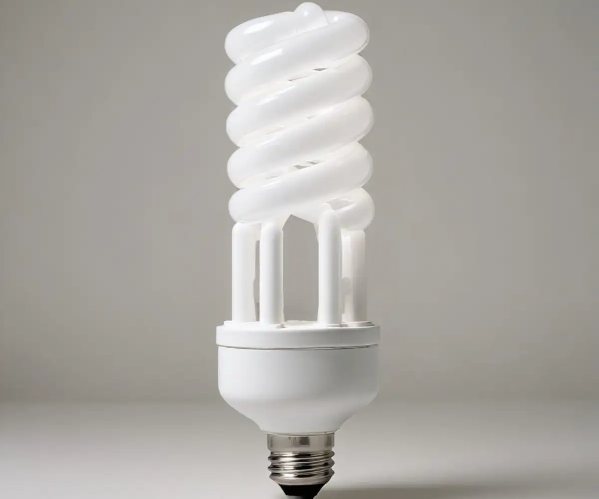 A white, 4-pin base, PLC 26-watt 3500K compact fluorescent light bulb with a quad tube shape against a plain background.