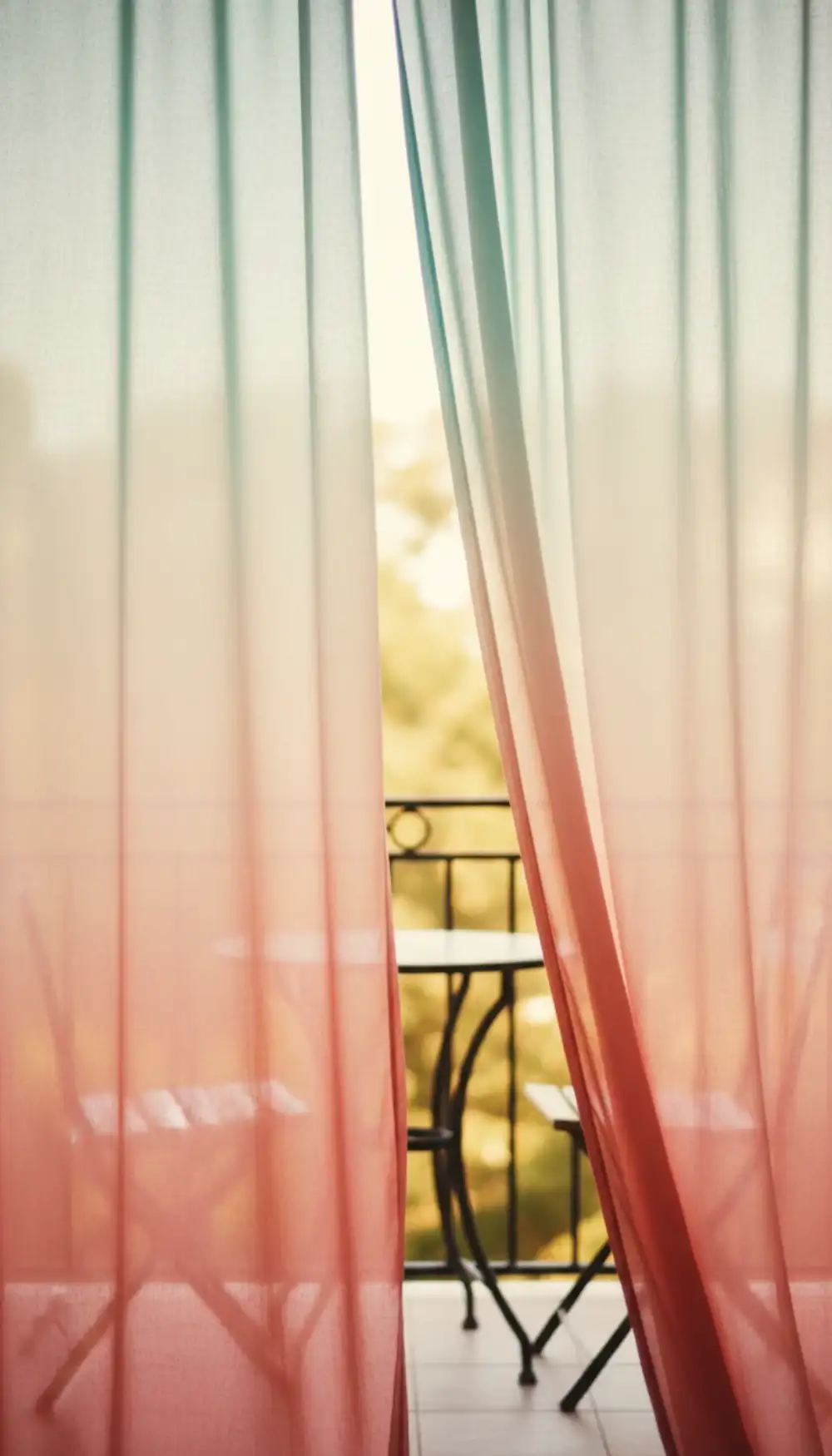 Sheer teal and coral curtains blowing in the wind on a balcony