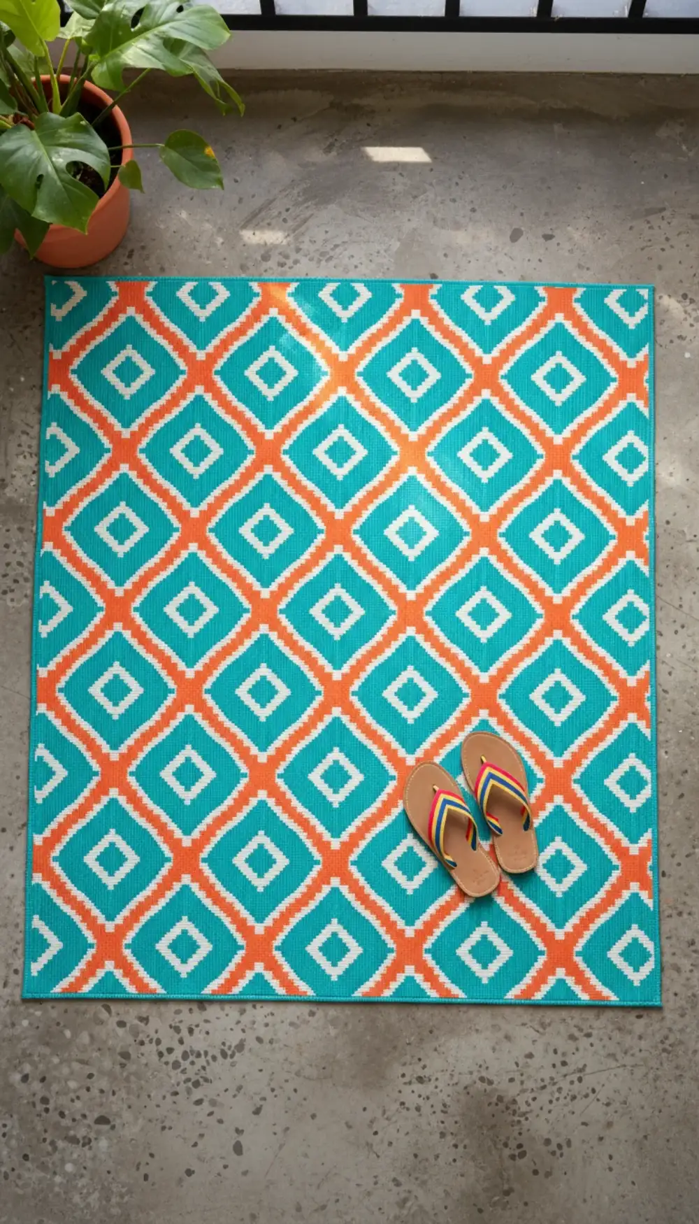Bright geometric patterned rug in teal and orange on a balcony floor