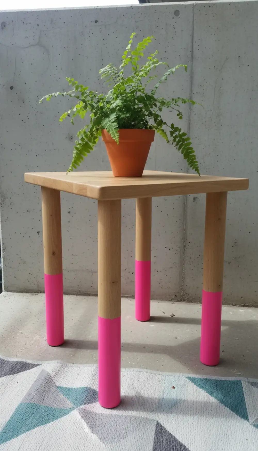 Wooden table with legs dip-dyed in bright neon pink paint