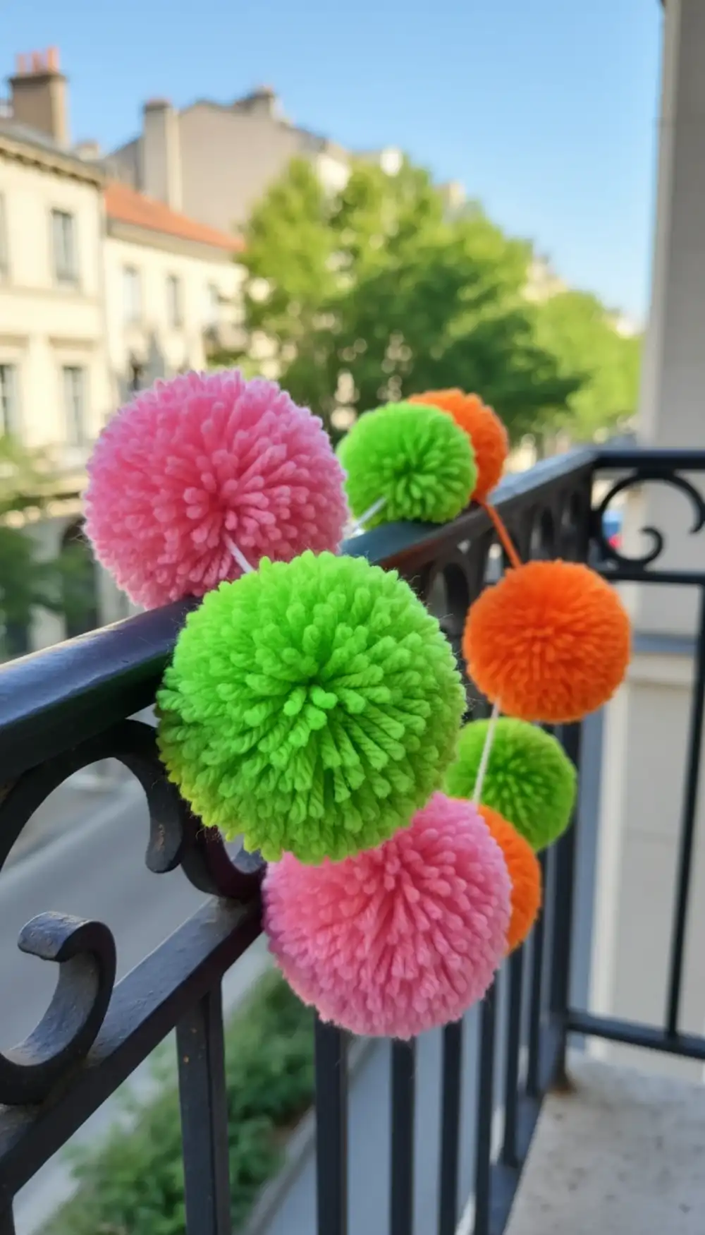 Colorful yarn pom-pom garland hanging along a balcony railing