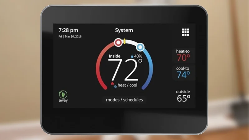 A wall-mounted smart thermostat with a blank, dark screen