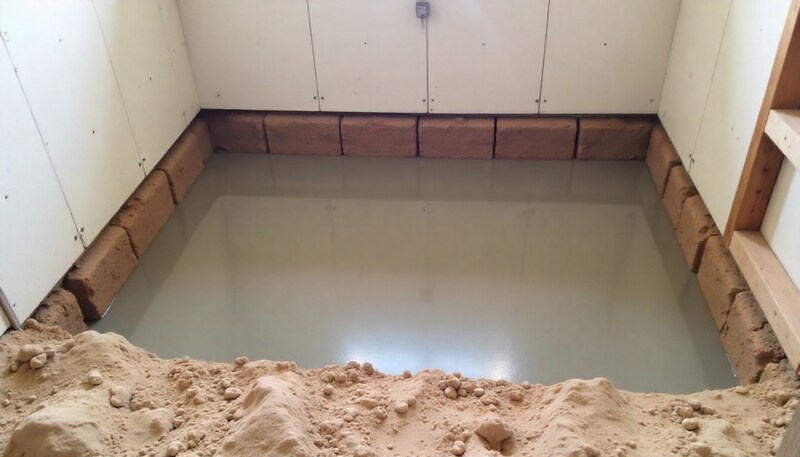 An excavated basement with exposed foundation footings, prepared for a new, deeper concrete floor pour.