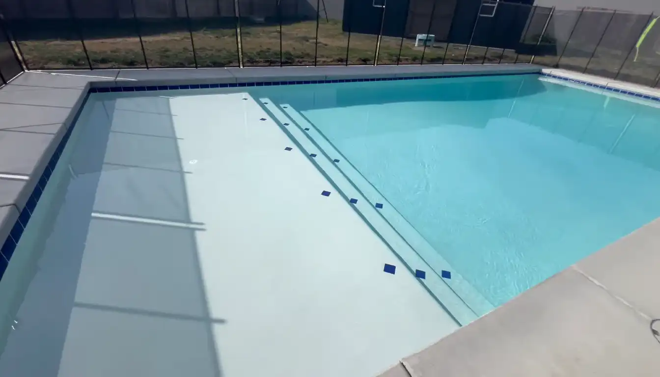 The textured surface of a light blue Pebble Fina swimming pool finish below the waterline.