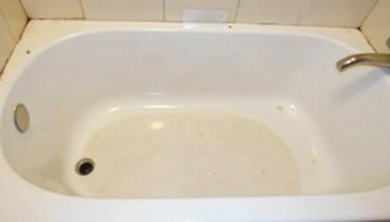 Peeling and cracked glaze on the surface of a white bathtub.